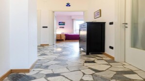 A hallway with a stone-patterned floor leading to a bedroom with a bed and dresser. - Modern Apartment with Panoramic City Views  (Milano)
