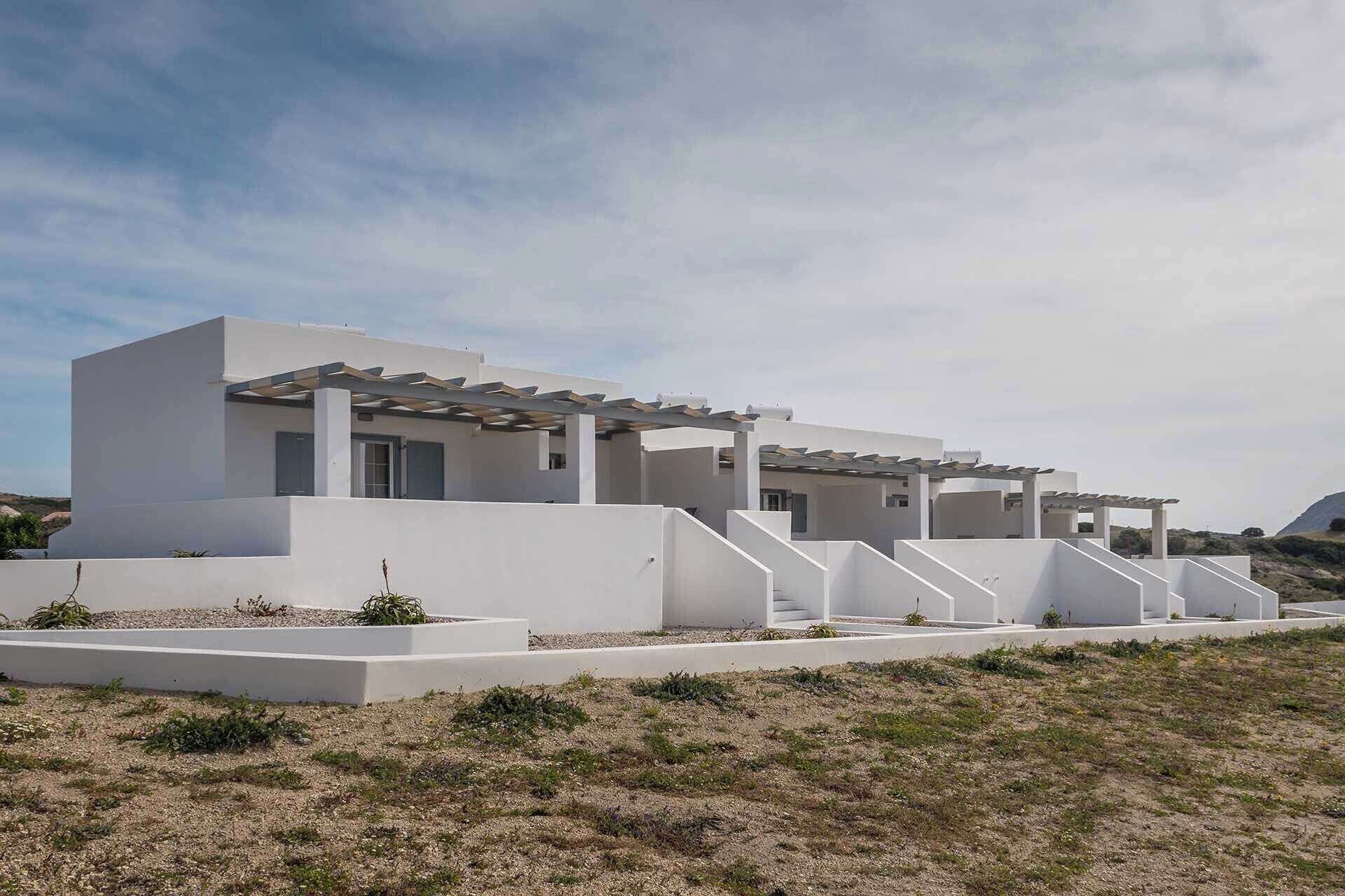 A modern, white building with a flat roof and a covered outdoor area.