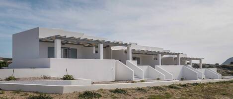 A modern, white building with a flat roof and a covered outdoor area.