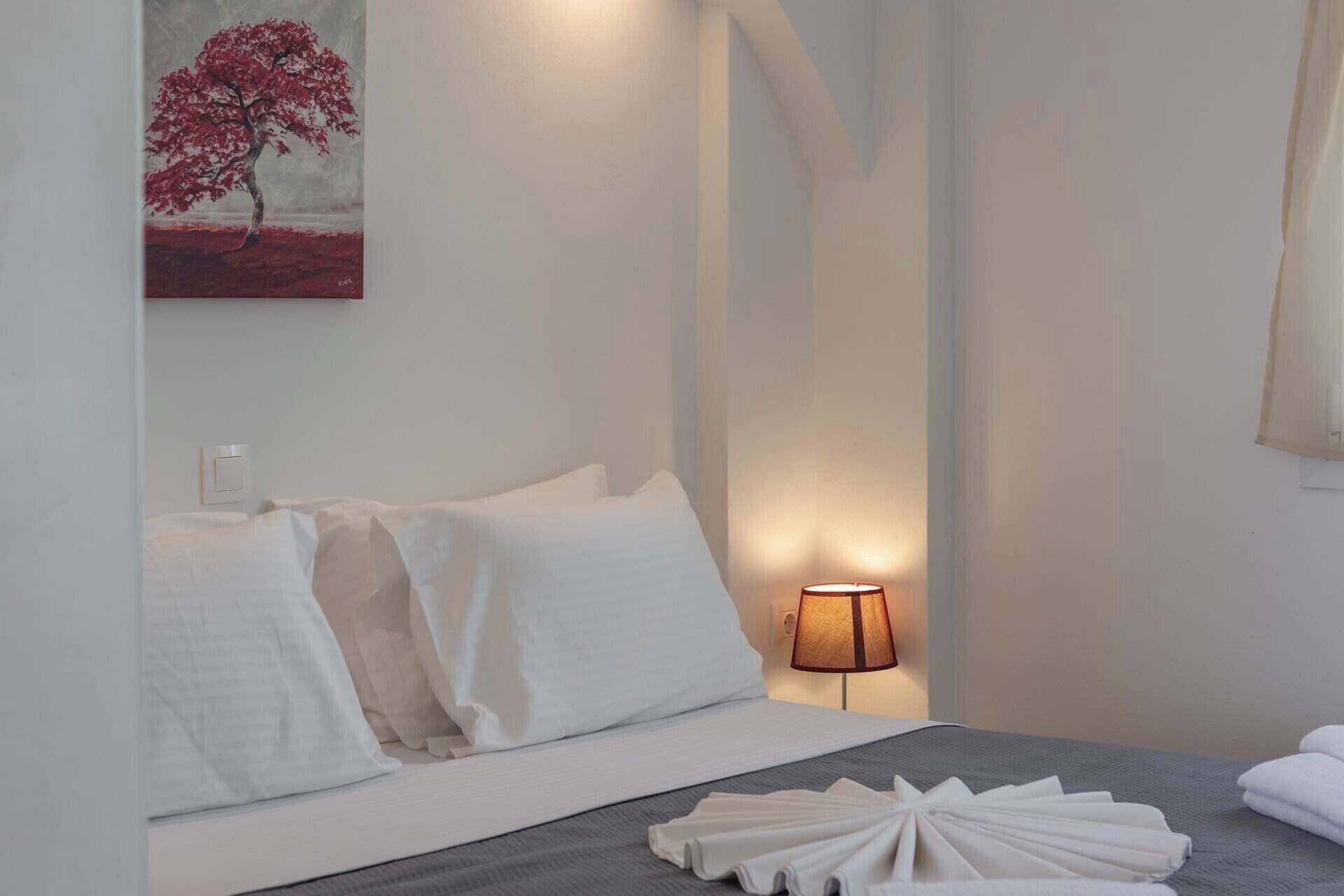 A hotel room with a bed, a bedside lamp, and a painting on the wall.