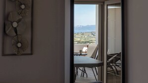 A balcony with a table and chairs, a view of a landscape with mountains, and a wall with decorative plates. - Sunset Village (Milos)
