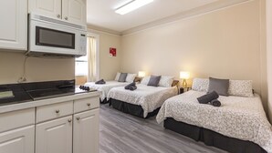 Ein Hotelzimmer mit zwei Betten, einer Küchenzeile und einer Mikrowelle.