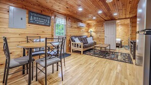 A log cabin interior with a dining area, a sofa, a refrigerator, and a sign reading "Wilderness Resort."