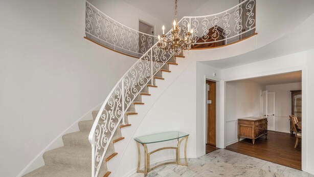Eine geschwungene Treppe mit einem Glastisch und einer Chandelier.