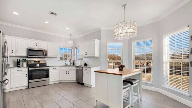 A modern kitchen with white cabinets, stainless steel appliances, and a central island.