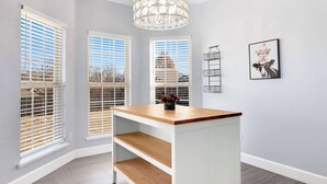 A room with a wooden table, white shelves, and a chandelier.