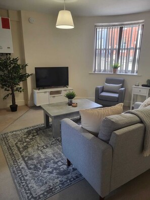 Relax in this stylish living room with a flat-screen TV, comfortable sofa, and armchair.