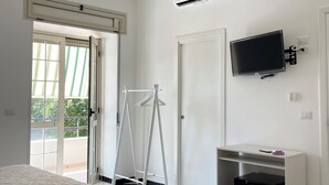 Una camera d'albergo con pavimento a scacchi, un letto con copripiumino fantasia, una TV a parete e una scrivania con un computer.