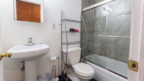 A bathroom with a white sink, toilet, and glass-enclosed shower. - Cozy STUDIO 1Full/2Twin beds near Empire State Building   (New York)