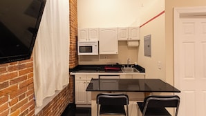 A compact kitchen with white cabinets, a microwave, a sink, and a black countertop. - Cozy STUDIO 1Full/2Twin beds near Empire State Building   (New York)