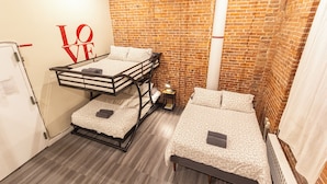 A room with a bunk bed, a single bed, and a brick wall. - Cozy STUDIO 1Full/2Twin beds near Empire State Building   (New York)