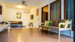 A spacious living room with a wooden bench, a sofa, and a television on the wall.