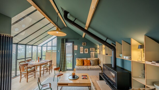 Una sala moderna con techo alto, ventanas grandes, chimenea y comedor.