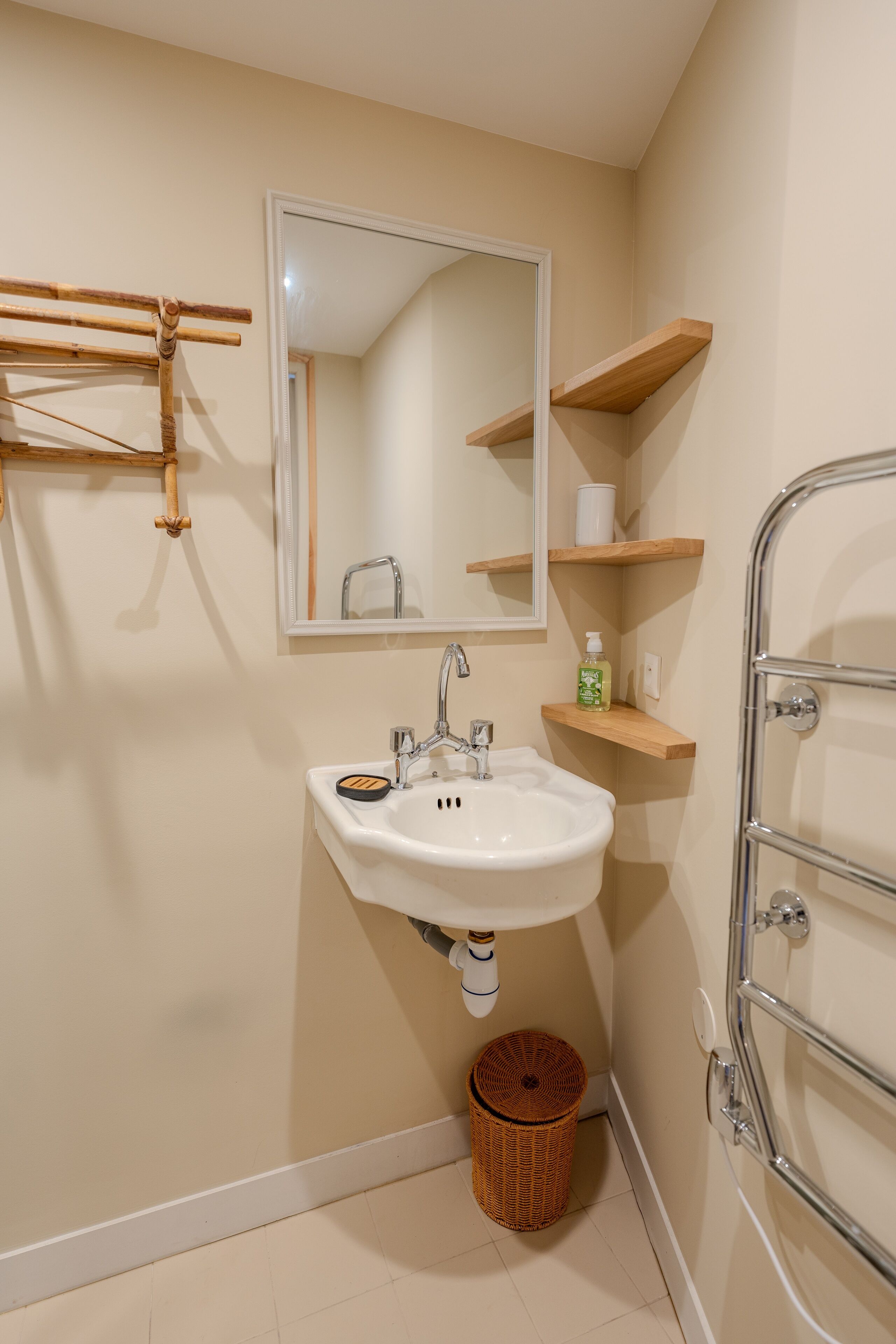 Ein Badezimmer mit Waschbecken, Spiegel und Holzregalen.