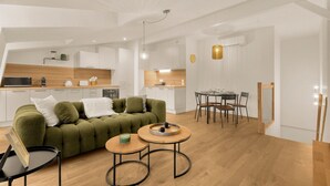 Ein zeitgemäßer Wohnbereich mit einem grünen Sofa, einem Esstisch und einer Küchenzeile.