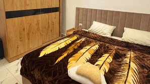 Een moderne slaapkamer met een groot bed, een houten garderobe en een nachtkastje.