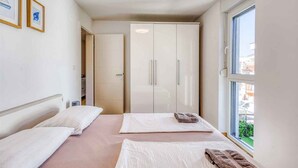A hotel room with two beds, a wardrobe, and a window with a view. - Holiday apartment with sea view (Njivice)