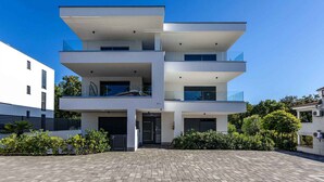 A modern multi-story building with balconies, a paved entrance, and surrounding greenery. - Holiday apartment with sea view (Njivice)