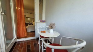 A small balcony with a white table, a red chair, and a white chair. - Holiday flat with balcony (Njivice)
