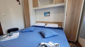 A compact bedroom with a single bed, a small desk, and a wall-mounted shelf. - Holiday flat with balcony (Njivice)