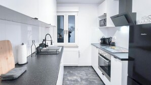Una cocina moderna con armarios blancos, encimera negra, horno empotrado y microondas.