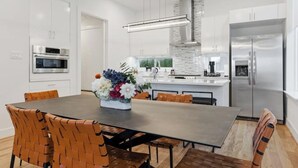 Una cocina moderna con armarios blancos, electrodomésticos de acero inoxidable y una isla central con un jarrón de flores.