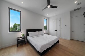 A bedroom with a bed, bedside tables, a ceiling fan, and a window.