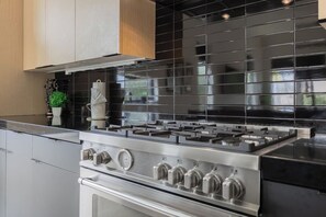 A modern kitchen with a stainless steel stove, black tiled backsplash, and wooden cabinets. - Modern & Spacious~Rooftop View of Downtown Dallas (Dallas)