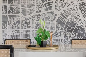 A table with a potted plant, a glass vase with reeds, and a black object on a tray. - Modern & Spacious~Rooftop View of Downtown Dallas (Dallas)