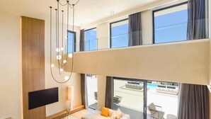 Une chambre d’hôtel moderne dotée d’une télévision à écran plat, d’un canapé, d’une petite table et offrant une vue sur la piscine.