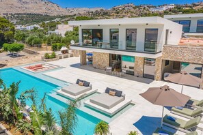 Una villa moderna con piscina, area relax all'aperto e facciata in pietra.