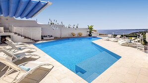 A pool with clear blue water, surrounded by lounge chairs and a view of the sea. - Villa Blu Marino by Villa Plus (Syracuse)