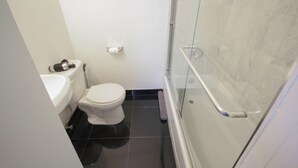 Un baño moderno con inodoro, lavamanos y cabina de ducha de vidrio.