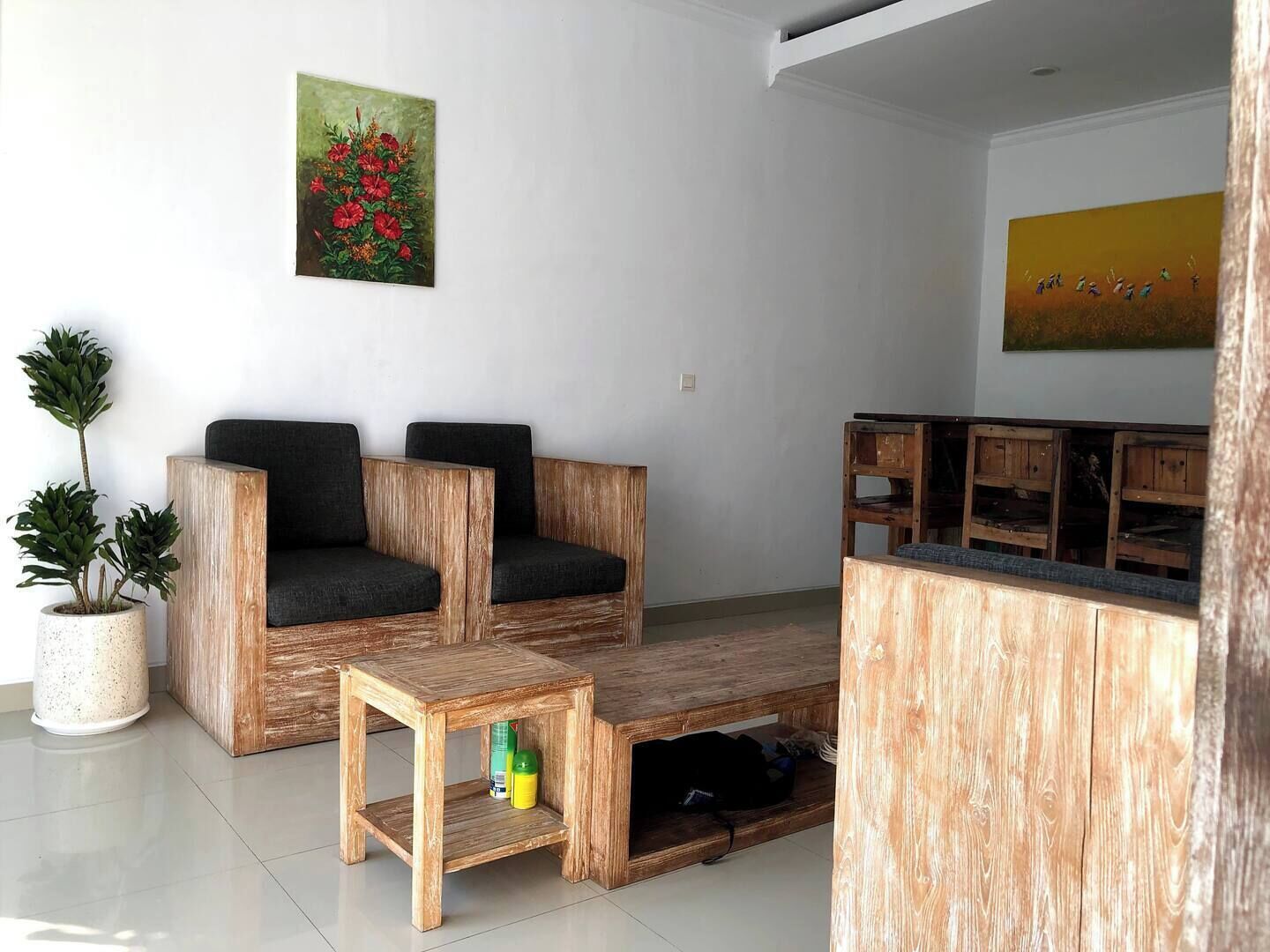 A modern living room with a wooden sofa set, a small wooden coffee table, and a potted plant.
