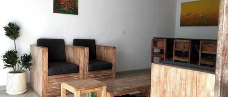 A modern living room with a wooden sofa set, a small wooden coffee table, and a potted plant.