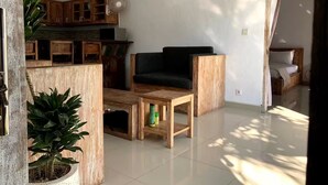 Uma sala de estar com uma mesa de centro de madeira, um sofá preto e um vaso com planta.