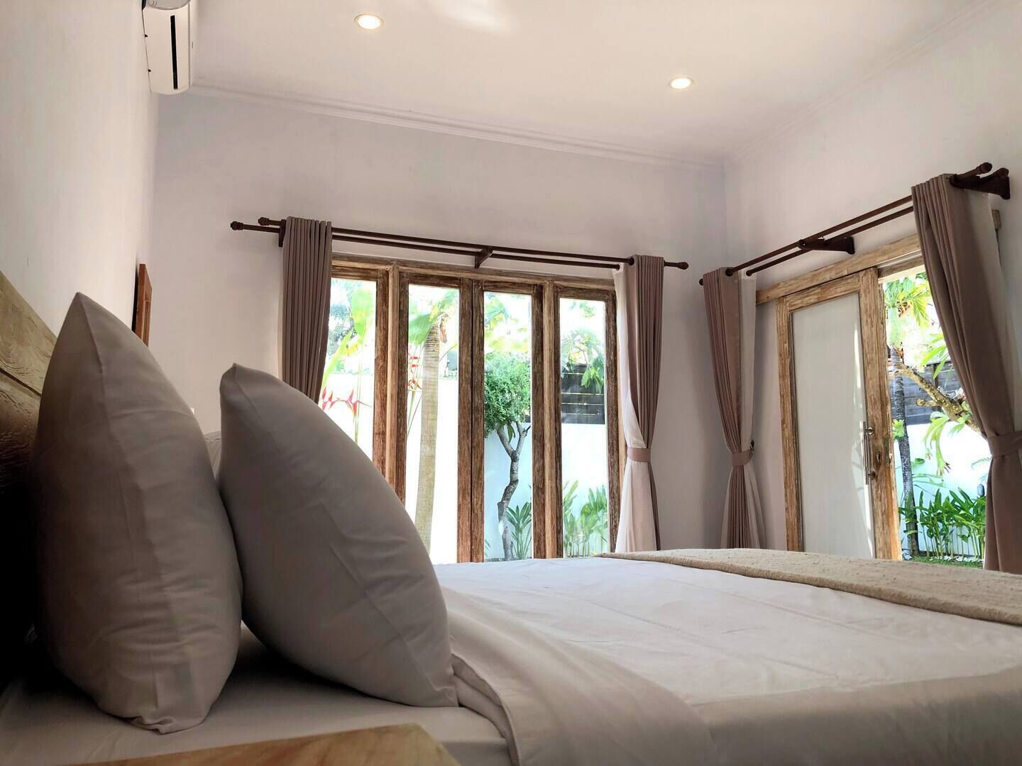 Ein Schlafzimmer mit Bett, Vorhängen und Blick auf Grünfläche.