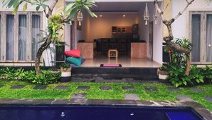 Uma casa moderna com piscina, plantas em vasos e interior bem iluminado.
