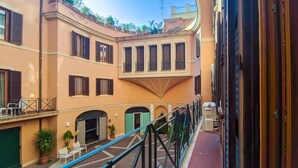 A courtyard with a curved building, multiple windows, and a balcony with outdoor furniture. - Trevi Ducal Palace I (Roma)