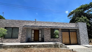 A modern building with a stone facade, a central entrance with a metal gate, and two wooden doors. - Beautiful country house in San Martin (pet and family friendly) (San Martín)