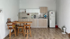 A compact kitchen with a dining area, featuring a wooden table and chairs, a refrigerator, and a microwave. - Beautiful country house in San Martin (pet and family friendly) (San Martín)