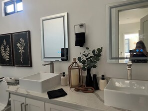 Un bagno moderno con due lavandini, uno specchio grande e decorazioni a parete.