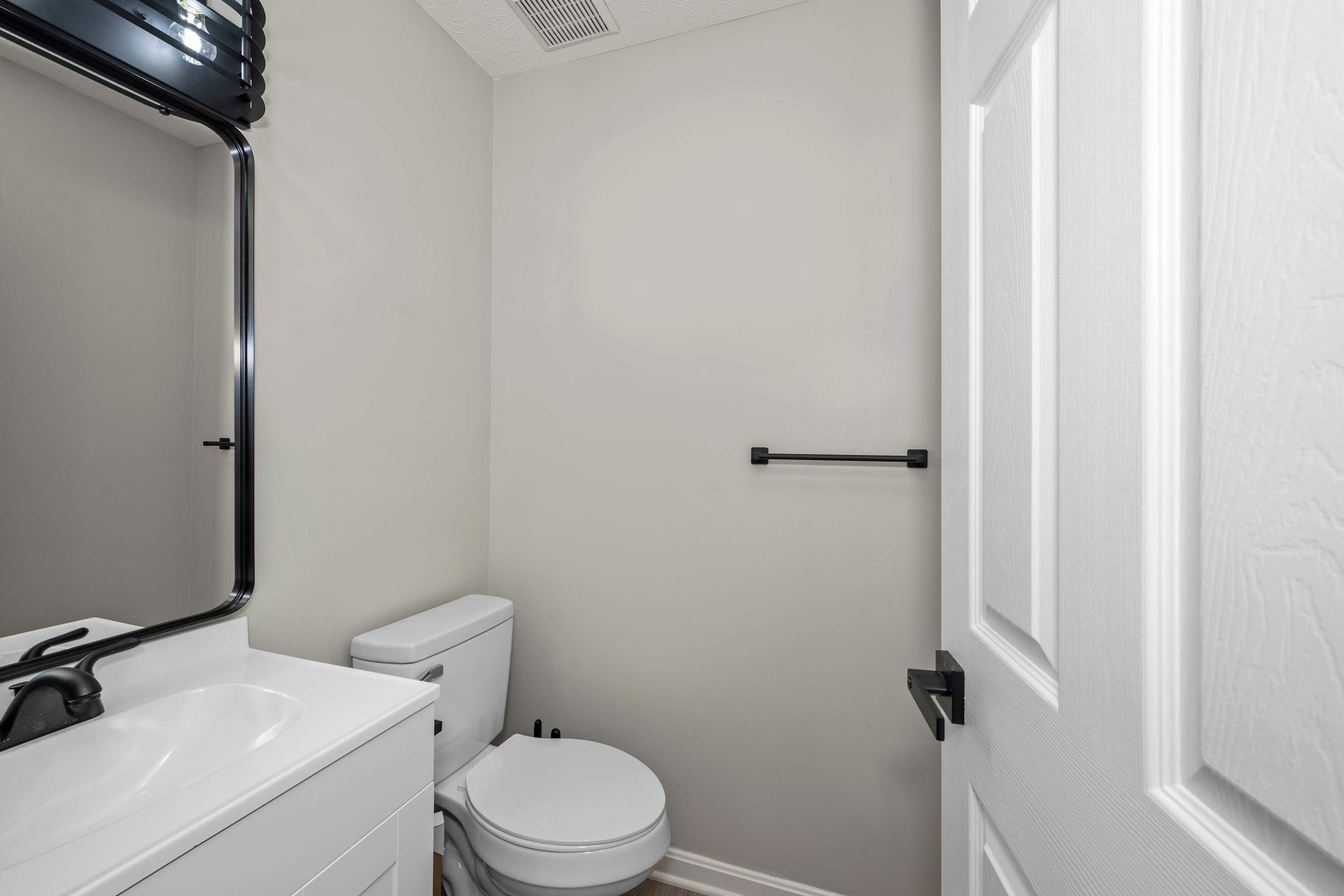 A bathroom with a white sink, toilet, and door.