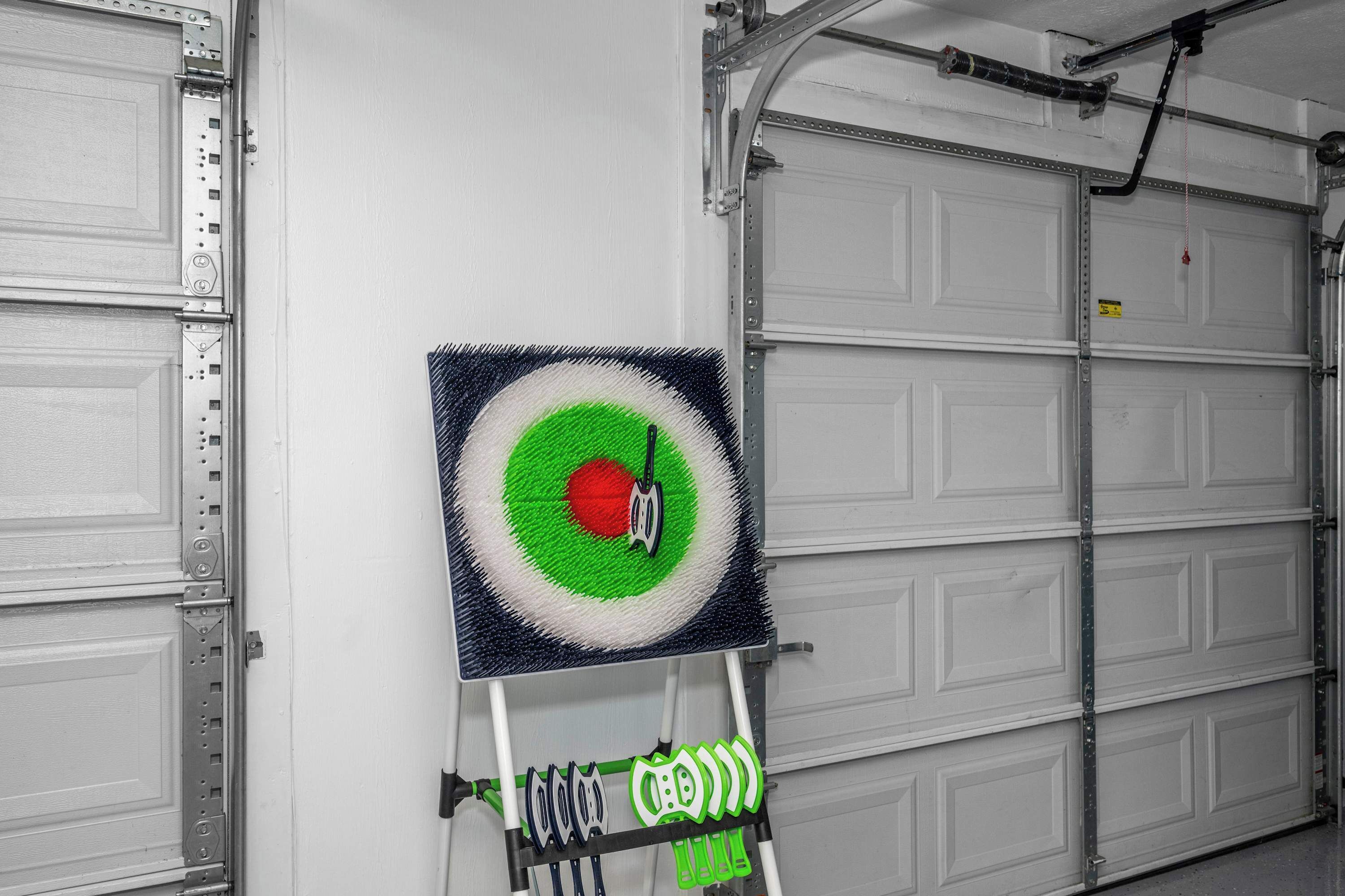 Eine Garage mit einem Zielscheibe auf einem Ständer, einer geschlossenen Garagentür und einer Metallleiter.