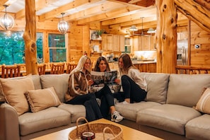 L'intérieur d'une cabane en rondins, avec un canapé, une table à manger et un coin cuisine.