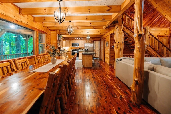 A wooden cabin interior with a dining area, kitchen, and living space.