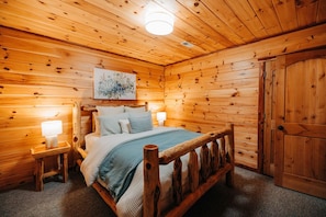 A wooden cabin bedroom with a bed, bedside lamps, a painting, and a wardrobe. - Rustic Cedar Inn | Luxury 6BR Lodge, Kids Loft (Rockbridge)