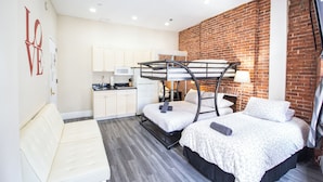 A compact room with bunk beds, a kitchenette, and a sofa.
