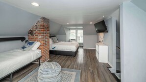 Une chambre avec deux lits, un mur en briques, une télévision et une fenêtre.