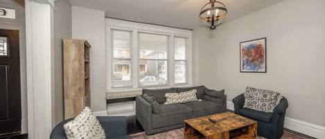 Ein Wohnzimmer mit grauem Sofa, einem Holztisch und einem gemusterten Teppich.
